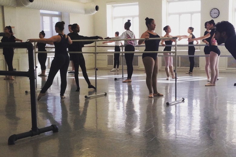 Ballet dancers rehearsing at the barre in a dance studio